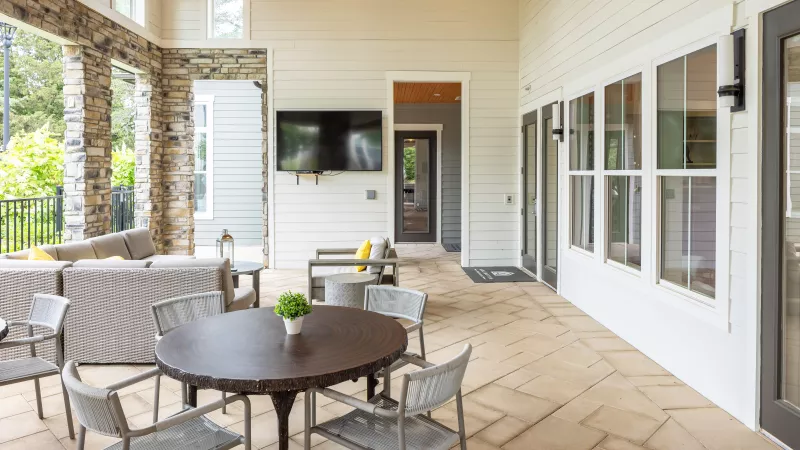 Patio seating area at Avery apartments featuring round tables, chairs, and mounted flat-screen TV.