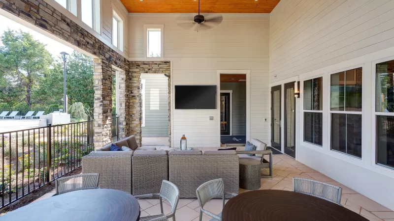 Spacious covered patio with wicker sectional sofa and wall-mounted TV at Avery apartments.
