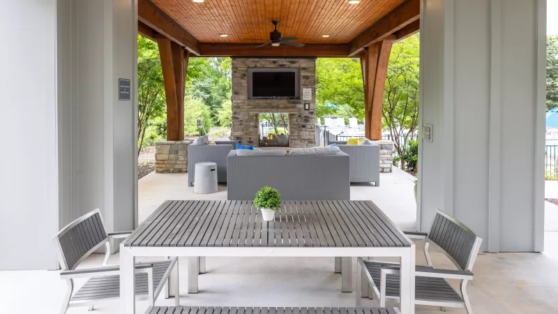 Pavilion at Avery apartments with picnic-style dining table, stone fireplace, and mounted TV.