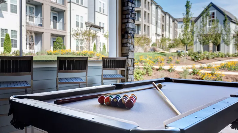 Close-up of pool table on outdoor patio at Avery apartments with view of community buildings.