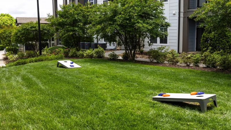 Lawn games area with cornhole boards on green grass at Avery at Turkey Creek Apartments.