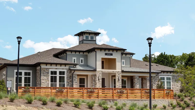 Wide view of Avery at Turkey Creek clubhouse with landscaped entry, stone details, and large windows.