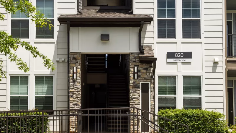 Building entrance at Avery at Turkey Creek Apartments with stone details, stair access, and signage.