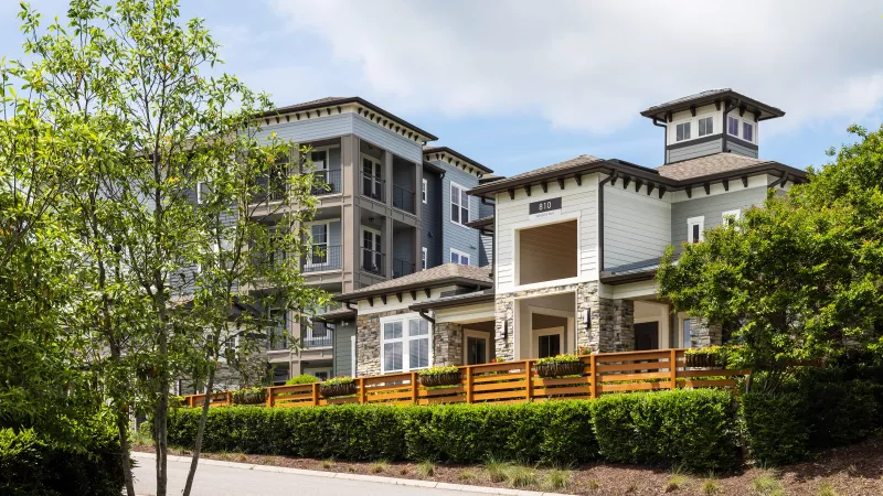 Community view of clubhouse and apartment buildings at Avery at Turkey Creek surrounded by greenery.