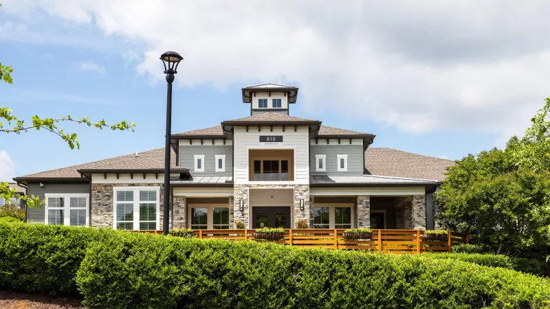 Front elevation of clubhouse at Avery at Turkey Creek Apartments with modern design and landscaped shrubs.