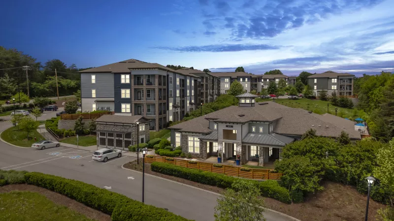 Evening aerial of Avery at Turkey Creek apartments and clubhouse illuminated with exterior lighting.