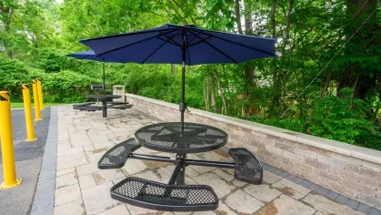 Outdoor patio area at Montgomery Plaza Apartments with black metal tables and chairs on a paved surface.