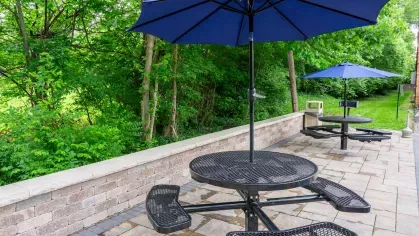 Community outdoor seating space with multiple black tables and greenery at Montgomery Plaza Apartments