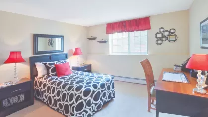 Royal Crest Estates Marlboro bedroom with large window – Bright bedroom with double bed, mirrored wall décor, and desk area near window for added light.