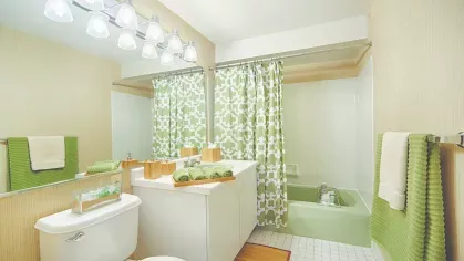 Bathroom with vanity and shower – Bright bathroom with white vanity, wide mirror, and green patterned shower curtain at Royal Crest Estates Marlboro.