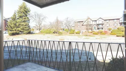 Private patio view – Covered private patio with black railing overlooking landscaped grounds and community buildings at Royal Crest Estates Marlboro.