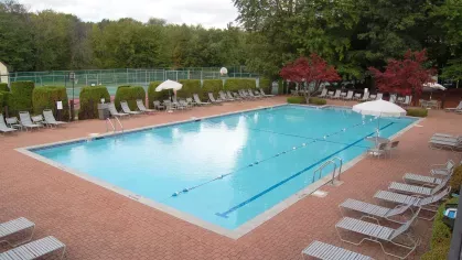 Swimming pool with lounge chairs – Large outdoor swimming pool with lounge seating, umbrellas, and surrounding greenery at Royal Crest Estates Marlboro.
