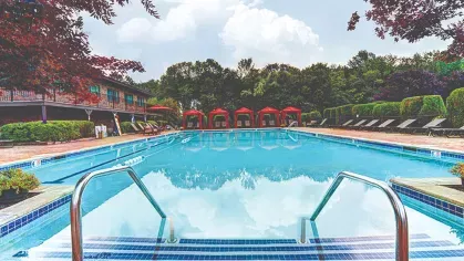 Resort-style pool with cabanas – Sparkling resort-style pool with red cabanas, lounge seating, and landscaped surroundings at Royal Crest Estates Marlboro.