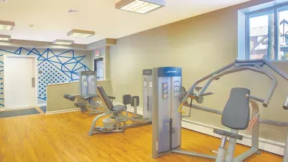 Royal Crest Estates Marlboro fitness center with strength training machines, wood-style flooring, and natural light from windows.