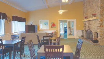 Clubhouse lounge at Royal Crest Estates Marlboro with stone fireplace, dining tables, upholstered seating, and television