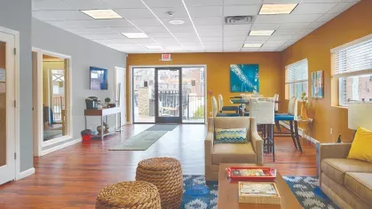 Clubhouse interior at Royal Crest Estates Marlboro with lounge seating, tall dining tables, and access to outdoor terrace