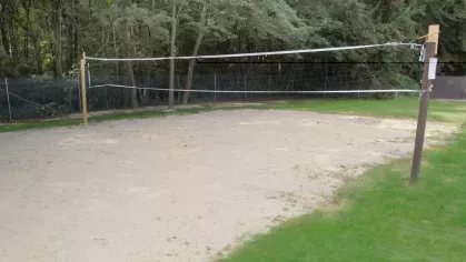 Sand volleyball court surrounded by grass and trees at Royal Crest Estates Marlboro