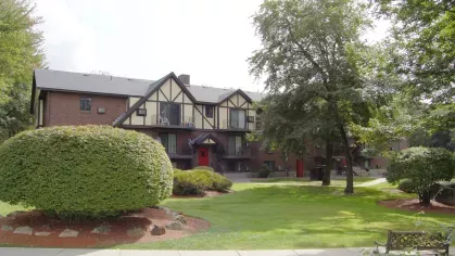 Community courtyard with Tudor-style apartments, manicured shrubs, and walking paths at Royal Crest Estates Marlboro.
