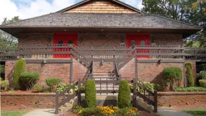 Brick clubhouse at Royal Crest Estates Marlboro with red double doors, wood railings, and manicured shrubs