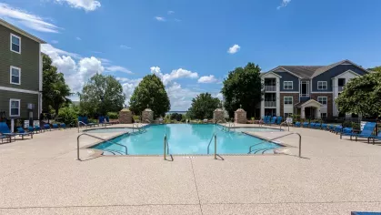 Large, expansive resort style pool with lounge chairs surrounding the perimeter. 
