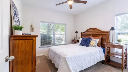 Bright, open bedroom with multiple windows and a ceiling fan. 