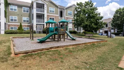 Large outdoor playground with multiple slides, surrounded by grass and trees. 