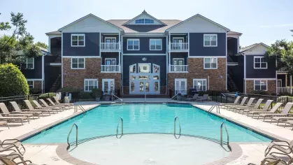 Large, sparkling, resort-style pool with lounge chairs around the perimeter. 