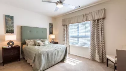 Large bedroom with updated ceiling fan and bright, open windows.