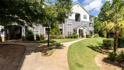 Well-manicured walkway surrounded by lush trees and green grass.