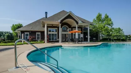 Steps with a handrail leading into the sparkling community pool. The River Run apartment clubhouse is visible in the background.