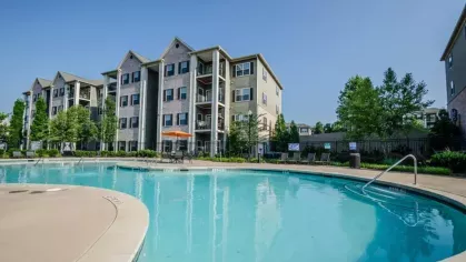 A view down the length of the resort-style swimming pool, surrounded by a spacious sundeck and apartment buildings.