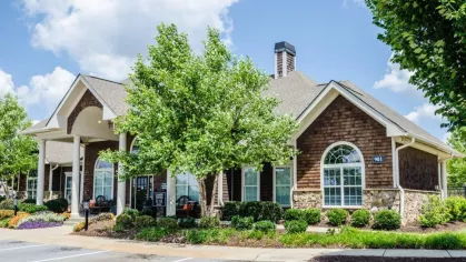 Beautifully landscaped leasing office with covered entry and seating at the apartment community.
