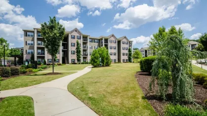 Manicured walking paths and open green spaces connecting buildings throughout the apartment community.