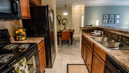 Open-concept kitchen with breakfast bar and view of the dining and living room in the apartment home.