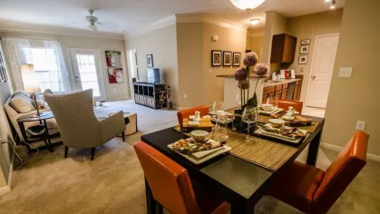 Spacious apartment interior with dining area, cozy living room, and natural light from large windows.