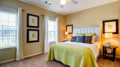 Primary bedroom with bright green bedding, tufted headboard, and framed botanical artwork.