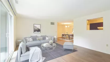 Large open-concept living and dining space with neutral-toned furniture, sliding glass doors, and hardwood-style flooring.