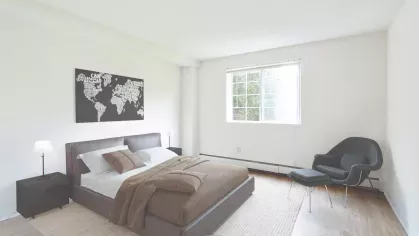 Sleek bedroom featuring a brown platform bed, neutral linens, and a world map artwork accenting the wall.