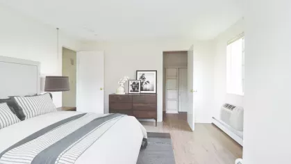 Inviting bedroom decorated with striped bedding, dark wood dresser, and built-in closet shelving for extra storage.