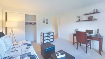 Guest bedroom styled with travel-inspired decor, writing desk, and sliding closet doors for convenient access.