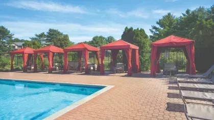 Row of red cabanas beside the pool deck, offering shaded outdoor seating and relaxation areas.