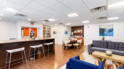 Community clubhouse with bookshelves, dining tables, and coffee station for residents to relax and connect.