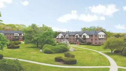 Expansive green lawn with walking paths connecting Tudor-style apartment buildings featuring red doors and balconies.