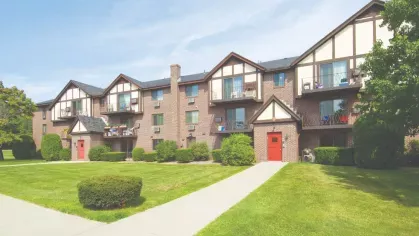 Brick apartment community with Tudor details, private balconies, and well-maintained grassy walkways.