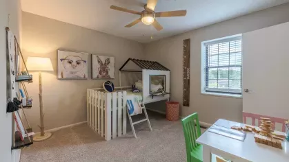 Large secondary bedroom with bright window and overhead fan and light.