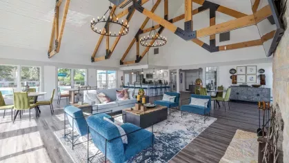 Large, expansive clubhouse with overhead lighting, large flatscreen TV, and multiple seating arrangements.