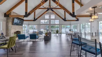 Large, expansive clubhouse with overhead lighting, large flatscreen TV, and multiple seating arrangements.