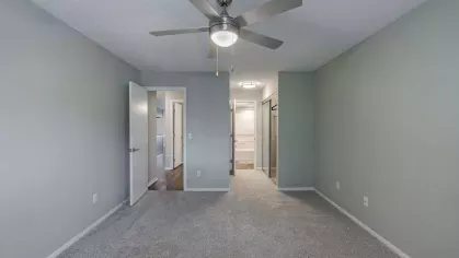 Large, open primary bedroom with attached bathroom and overhead ceiling fan and light.