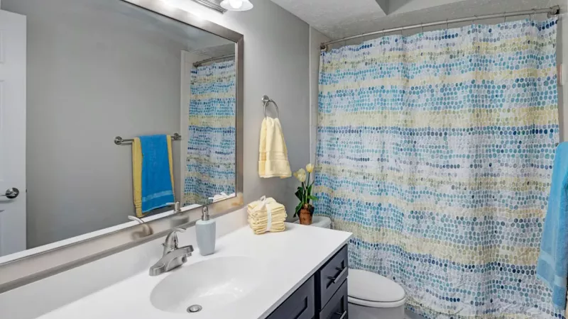 Shower/tub combination located in a well-lit bathroom with an oversized vanity and mirror.