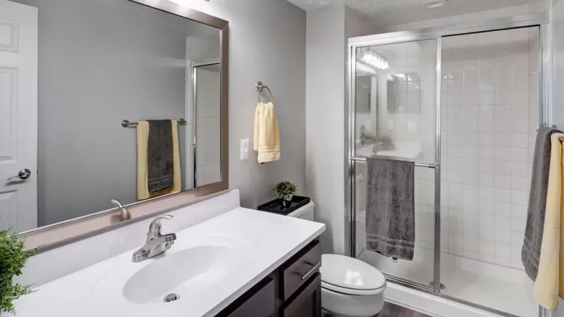 Full, standing shower located in the primary bathroom with bright overhead light fixtures and an oversized counter.